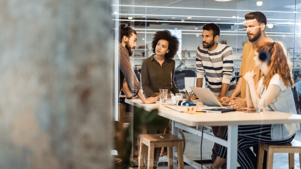 Multiple people working at a desk to the right of a wall